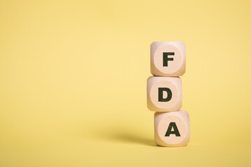 FDA, U.S. Food and Drug Administration Acronym on Wooden cubes isolated on Yellow copy space - obrazy, fototapety, plakaty