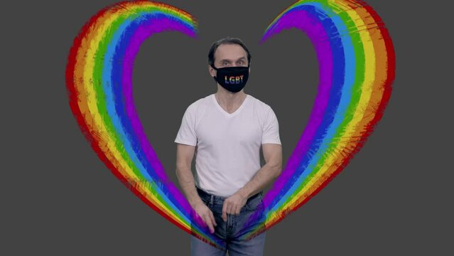 Gay man in lgbt mask and white t-shirt walks making heart love gesture by hands, alpha channel included in full hd footage