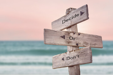 decide or dont text quote written on wooden signpost by the sea. Positive pink turqoise pastel theme.