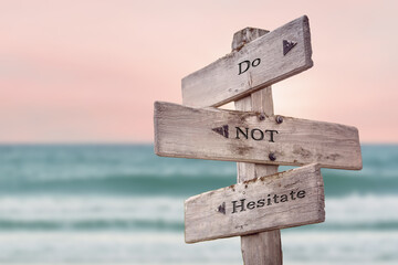 do not hesitate text quote written on wooden signpost by the sea. Positive pink turqoise pastel theme.