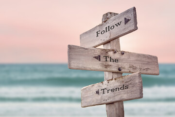 follow the trends text quote written on wooden signpost by the sea. Positive pink turqoise pastel theme. © Jon Anders Wiken