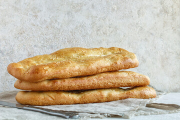 Freshly baked Italian traditional homemade focaccia bread on a light background.