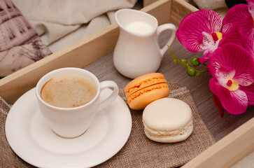 Morning coffee with milk and macarons on a tray in bed