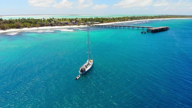 Yacht anchored in clear blue water near tropical atoll