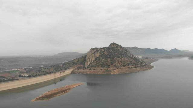 Aerial images showing a huge reservoir from 120 meters high.  In the background a large mountain with a medieval castle on it.  Camera pans to the right showing more reservoir