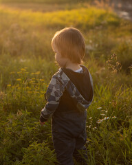 A little boy outside in the summer next to a water column