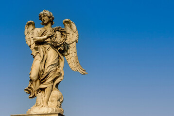 Fototapeta na wymiar Rome, Italy - June 2000: A stone statue of an angel on a blue sky background