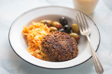 Vegetable burger with sunflower seeds, olives and raw vegetable salad with banana smoothie