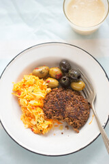 Vegetable burger with sunflower seeds, olives and raw vegetable salad with banana smoothie