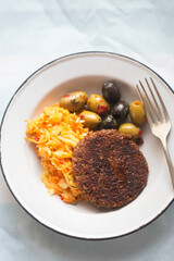 Vegetable burger with sunflower seeds, olives and raw vegetable salad with banana smoothie