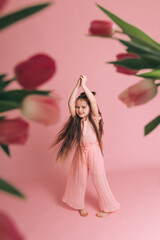 Fototapeta na wymiar Portrait of a girl with tulips on pink background.