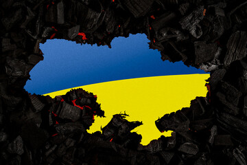 Ukraine against the background of burnt coals. The colors of the Ukrainian flag are blue and yellow on a dark back.