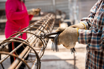 Labor worker using wire pliers to tie the base of steel for the construction of poles and the...