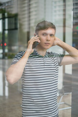 Portrait of young caucasian man in casual clothes making phone call