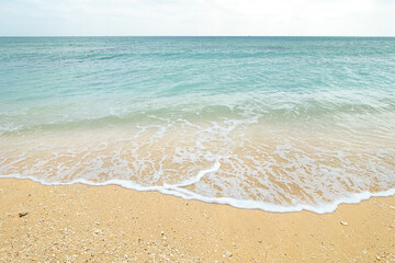 A  beach with waves, small shells and finely broken coral