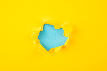 Naklejka na ściany i meble yellow and blue Hole in the paper with torn sides.