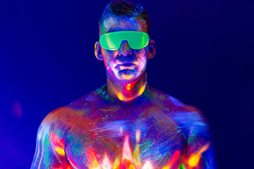 Portrait of a pumped-up man at a disco. Fluorescent paint on face in with UV light