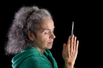 Woman praying with syringe in hands