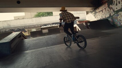 Young biker performing rail stunt at urban skate park. Rider racing on bmx.