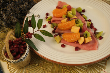 Pancakes. Pink sweet dough with fruits and honey. Tangerines, kiwi, pomegranate seeds. Floral background. Delicious breakfast at home or in a cafe. Selective focus. Shrovetide menu. carnival baking