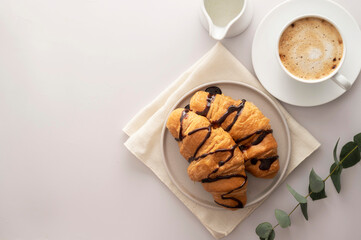 Croissants with chocolate and coffee cup on bright background. Copy space