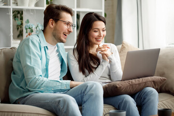 Young couple enjoy Social teleconferencing with their family via laptop screen in condominium social distancing