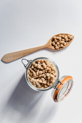 Vista superior de una cuchara de madera y un tarro de cristal lleno de habas de soja texturizada gruesa. Concepto de alternativas veganas a la carne. Proteína vegetal. Cocina vegetariana. 