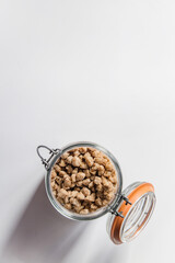 Vista cenital de un tarro de cristal lleno de habas de soja texturizada gruesa. Concepto de alternativas veganas a la carne. Proteína vegetal. Cocina vegetariana. Imagen vertical. Espacio en blanco.