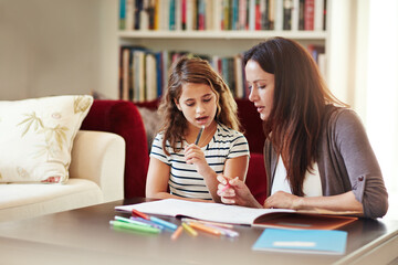 Trying to figure it out together. Shot of a beautiful mother helping her adorable daughter with her homework at home.