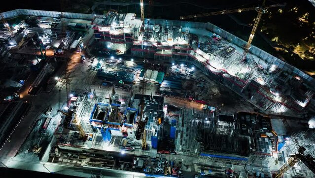 Hyperlapse time-lapse of under construction site project, crane, and car traffic transportation at night in Asia city. Drone aerial view. Industrial business or civil engineering technology concept