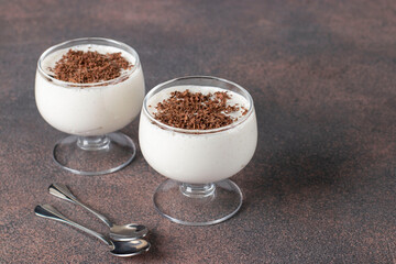 Homemade pudding jelly of cream or milk sprinkled with chocolate chips in two cups on a brown...