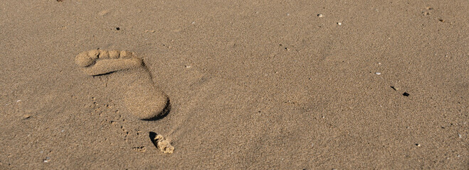 Traces of human feet on the sand near the ocean's water on the beach. Footprint on a sand. Summer,...
