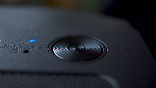 Macro video of a person turning on and off a personal computer with his finger. Technology concept. Turning on a device with a shallow depth of field.