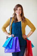 Brilliant bargain hunter. Pretty young woman smiling at the camera while carrying colourful shopping bags.