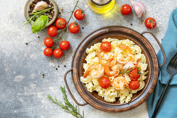 Mediterranean cuisine, seafood diet. Italian creste di gallo pasta with grilled prawns and tomatoes on a stone tabletop. Top view flat lay. Copy space.