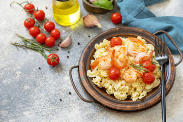 Mediterranean cuisine, seafood diet. Italian creste di gallo pasta with grilled prawns and tomatoes on a stone tabletop. Copy space.