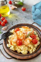 Mediterranean cuisine, seafood diet. Italian creste di gallo pasta with grilled prawns and tomatoes on a stone tabletop.