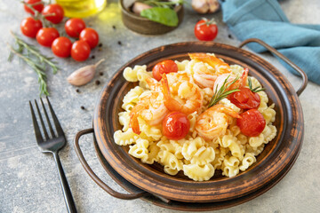 Mediterranean cuisine, seafood diet. Italian creste di gallo pasta with grilled prawns and tomatoes on a stone tabletop.