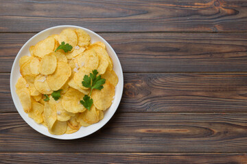 Potato chips on bowl with napkin on colored background. Delicious crispy potato chips in bowl. Space for text. Top view