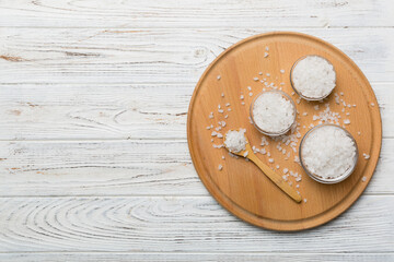 A wooden bowl of salt crystals on a wooden background. Salt in rustic bowls, top view with copy space