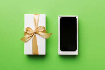 Opened gift box with gold ribbon and smartphone on color background, top view. Blank open box packaging mockup , Template for your design - branding mockup