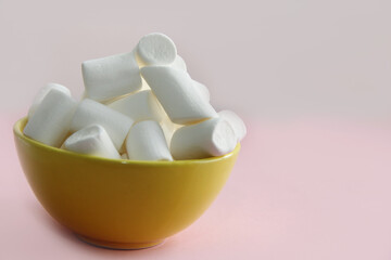 white marshmallow in a yellow plate on a pink background