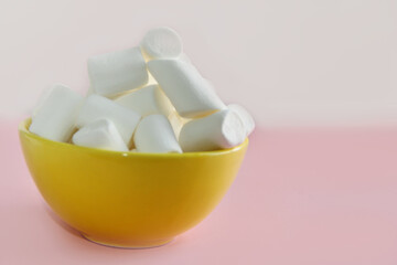 white marshmallow in a yellow plate on a pink background