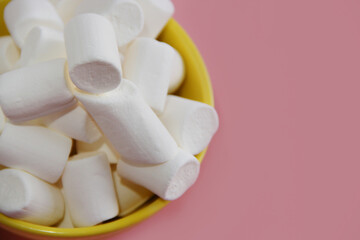 white marshmallow in a yellow plate on a pink background