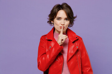 Young secret woman 20s wear red leather jacket say hush be quiet with finger on lips shhh gesture...