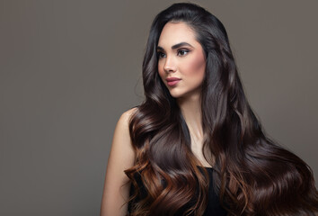 Brunette woman with black wavy ombre hair. Portrait on a gray background © Alena