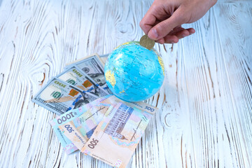 Ukrainian money hryvnia and dollars with a globe on a white wooden background. The war in Ukraine is inflation and financial assistance from the world.