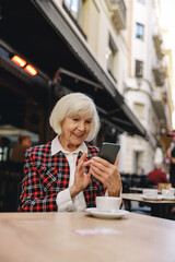 Photo of charming woman using smartphone outdoors