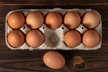 Happy Easter. Easter eggs. Chicken brown eggs closeup top view On the table. A carton crate of...