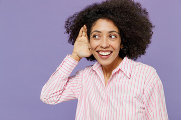 Young curious nosy woman of African American ethnicity 20s wear pink white striped shirt try to...